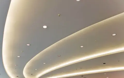 Nowoczesny podwieszany sufit z ukrytym oświetleniem LED tworzy łagodne, faliste linie, dodając przestrzeni elegancji.