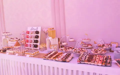Słodki stół weselny dla 80 osób: mnóstwo ciast, babeczek i donutów.