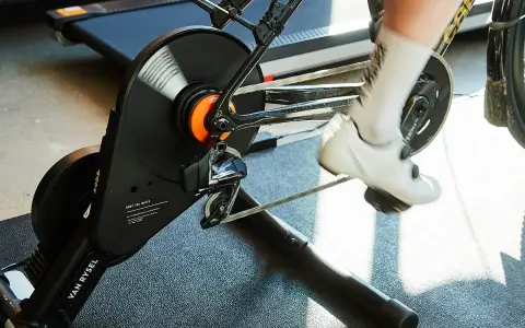 A cyclist's feet pedal on a bike connected to a magnetic resistance trainer, ready for an indoor workout.
