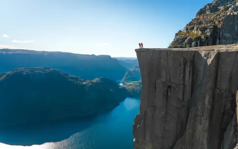 Två personer står på kanten av en klippa med utsikt över Stavangerfjorden.