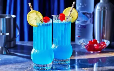 Dwa błękitne drinki Kamikaze, ozdobione cytryną i wiśnią, idealne do picia w letni wieczór.