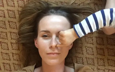 Kiedy mam dość swojego dziecka, jego rączka w paski zasłania mi oko. Leżymy na dywanie.
