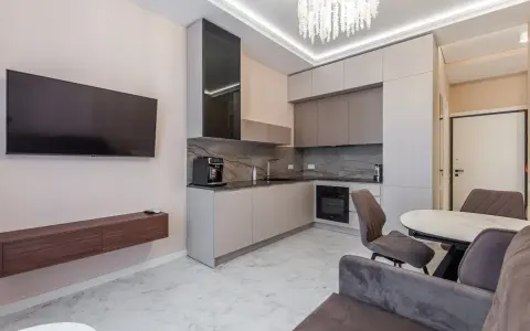 Un moderno open space lungo e stretto con cucina a vista, zona TV e tavolo da pranzo.
