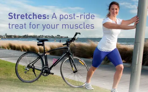 A woman performs a bicycle stretch, leaning on a pole after a ride by the beach.