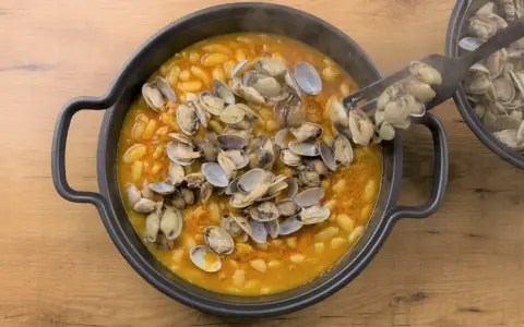 Plato humeante de fabes con almejas, un manjar tradicional.