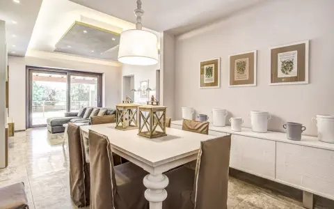 Un'elegante casa stile shabby chic moderno con tavolo da pranzo, divano e quadri botanici.