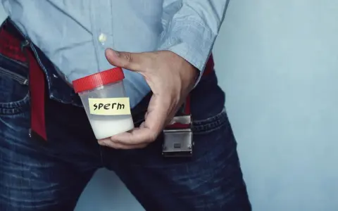 Mężczyzna trzyma pojemnik z białą substancją, której kolor spermy jest widoczny.