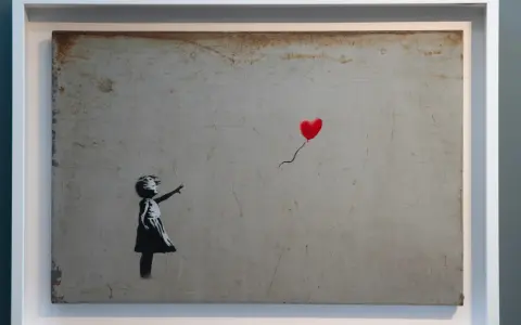 Dziewczynka sięga po czerwony balon w kształcie serca. To słynne dzieło Banksy'ego, artysty znanego z prowokacyjnych prac.