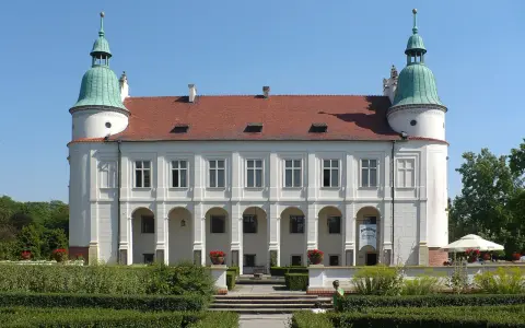 Baranów Sandomierski atrakcje: Zamek z arkadowym podcieniem i zielonymi wieżyczkami, otoczony zadbanym ogrodem.