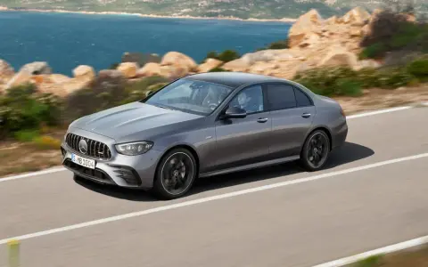 Sedán gris deportivo en carretera costera, comparando la elegancia de la clase C con la sofisticación de la clase E.