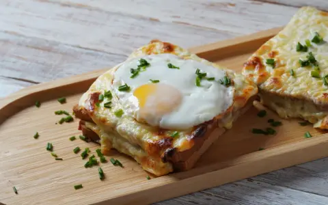 Croque monsieur con huevo frito y cebollino, un delicioso sándwich gratinado.