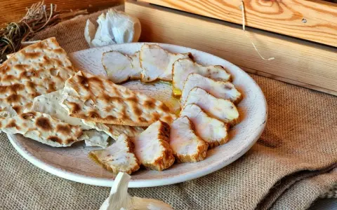Lomo de orza en rodajas, servido con pan crujiente y ajo. Un plato rústico y delicioso.