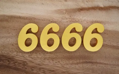 Quatre chiffres dorés 6666 sur fond de bois. Le 6666 signification est souvent lié à l'abondance et à la prospérité.