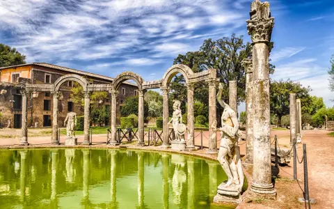 Starożytne ruiny i rzeźby w Villa d'Este odbijają się w zielonym stawie.