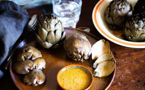 Artichauts prêts à être dégustés, accompagnés d'une sauce savoureuse. Une idée pour une recette artichaut simple et délicieuse.