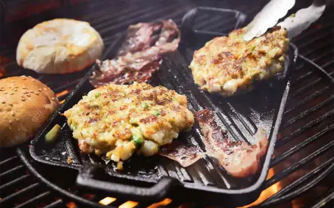 Burger-Patties und Brötchenhälften werden auf einem Grillrost zubereitet. Das Burger grillen verspricht einen köstlichen Genuss.
