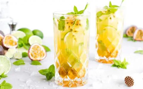 Zwei erfrischende Passion Fruit Mojitos mit Minze und Limette, umgeben von frischen Früchten und Eis.