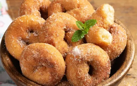 Rosquillas de la abuela esponjosas, cubiertas de azúcar y canela, con una ramita de menta. ¡Un placer casero!