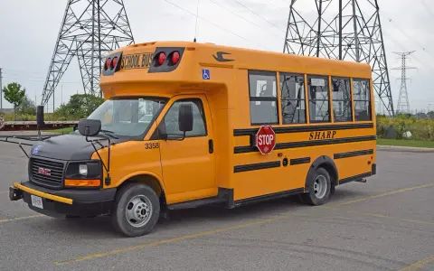 Żółty autobus szkolny GMC z napisem "SHARP" i znakiem STOP. Zastanawiasz się, ile kosztuje autobus?