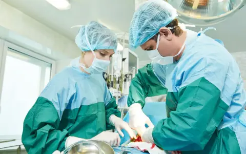 Chirurdzy w sterylnych strojach podczas operacji. Temat: usunięcie jajników skutki uboczne.
