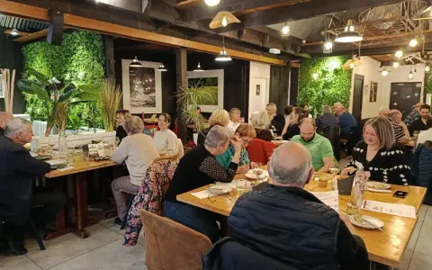 Un dîner convivial dans un restaurant à l'ambiance chaleureuse, où les convives savourent des mets qui incarnent la définition du "produit du terroir".