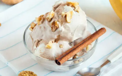 Un délicieux bol de glace au yaourt, garni de noix et d'un bâton de cannelle. Un délice rafraîchissant !