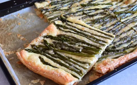 Deliziosa pasta sfoglia con asparagi e formaggio filante, appena sfornata su una teglia.