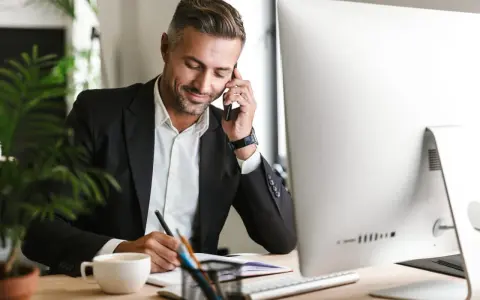 Uomo d'affari al telefono, scrive appunti. Potrebbe essere un agente immobiliare che discute di quanto guadagna un agente immobiliare.