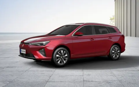 Czerwony MG5 Electric, kombi, stoi na betonowym placu z widokiem na morze.
