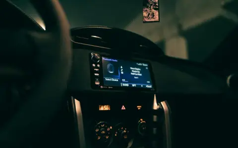 Wnętrze samochodu z włączonym radiem, na ekranie wyświetla się "Bluetooth Audio" i tytuł piosenki. Zastanawiasz się, co to jest treble w kontekście dźwięku? To wysokie tony.