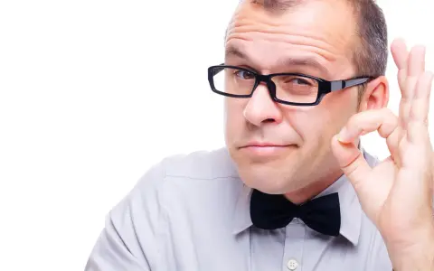 Mężczyzna w okularach i muszce pokazuje gest "OK". Okulary leżą idealnie na nosie, podkreślając jego pewność siebie.
