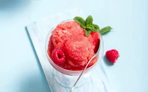 Erfrischendes Slush Eis mit Himbeeren und Minze in einem Glas, bereit zum Genießen.