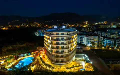 Nocny widok na lśniący hotel Michell z basenem i oświetlonymi pokojami. Wiele pozytywnych michell hotel spa opinie potwierdza jego urok.
