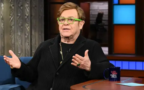 Elton John w zielonych okularach, z bogatym majątkiem, opowiada w programie.