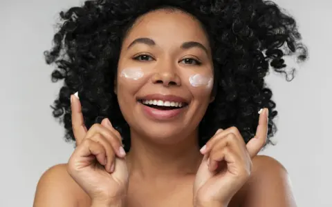 Donna sorridente con crema sul viso. La crema è non comedogeno, significa che non ostruisce i pori.