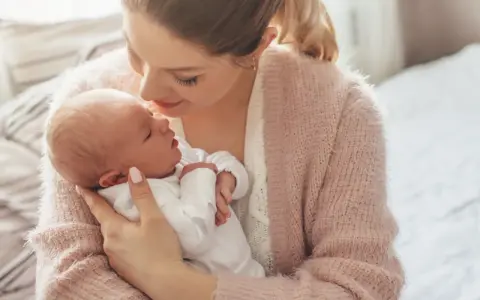 Delikatna pozycja do odbijania noworodka w ramionach mamy, która tuli go z miłością.