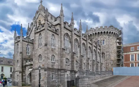 Kamienne mury i strzeliste wieże zdobią zamek w Dublinie. Gotycka architektura i chmurne niebo tworzą majestatyczny widok.