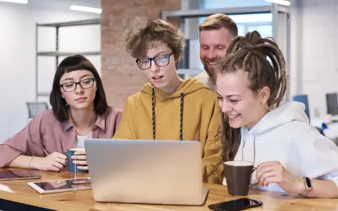 Zespół pracuje nad projektem, dyskutując przy laptopie. Może to być ich **praca** jako **ratownik KPP**.