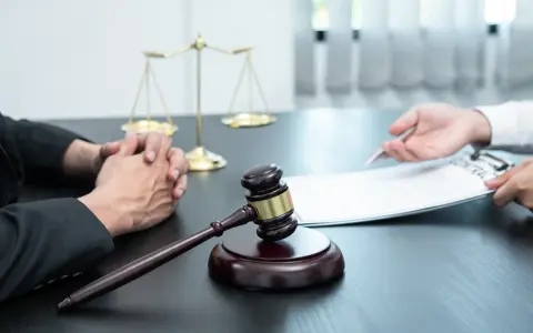 Sądowy młotek i waga sprawiedliwości symbolizują prawo. Rozmowa o dziedziczeniu i zachowku w kancelarii prawnej.