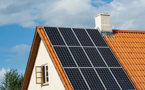 Solceller på ett tegeltak. En öppen fönsterlucka syns på husets gavel. Vissa oroar sig för solceller brandrisk.