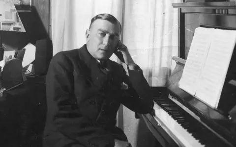 Karol Szymanowski, zamyślony przy fortepianie, z nutami na pulpicie.