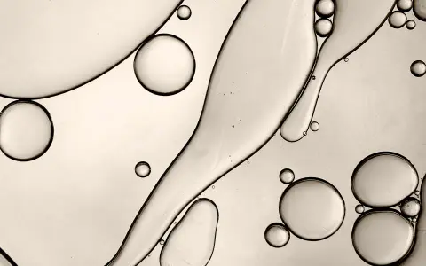 Gocce d'olio e acqua creano forme astratte, ricordando la struttura di un c13-15 alkane.