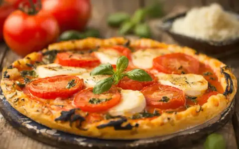 Délicieuse tarte tomate mozza, garnie de basilic frais et de tomates juteuses, prête à être dégustée sur un fond rustique.