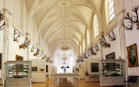 Prunkvolle Halle des deutschen Jagd- und Fischereimuseums mit Geweihen, Waffen und Gemälden.