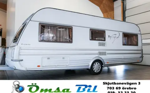 Vit husvagn, en av Tabbert modeller, står i ett garage.