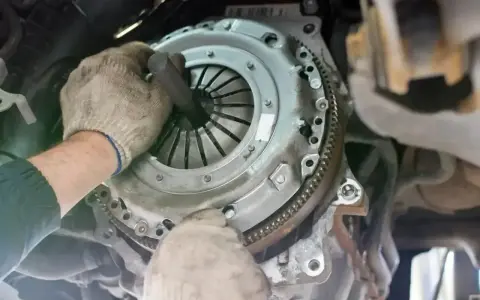 Mechanik w rękawiczkach montuje tarczę sprzęgła, przygotowując wysprzęglik sprzęgła do pracy.