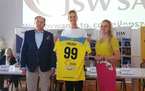 Trzy osoby pozują z koszulką z numerem 99 i nazwiskiem PIELESZ. W tle logo JSW i napisy związane z firmą, być może z okazji wydarzenia w MTS Żory.