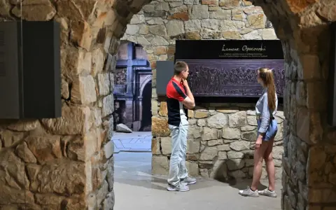 Zwiedzający podziwiają fragment nagrobka "Lament Opatowski" w kamiennych murach.