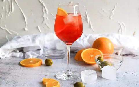 Ein Aperol Spritz mit Orangenscheibe und Eis. Orangen, Oliven und Eiswürfel deuten auf Aperol Spritz Varianten hin.