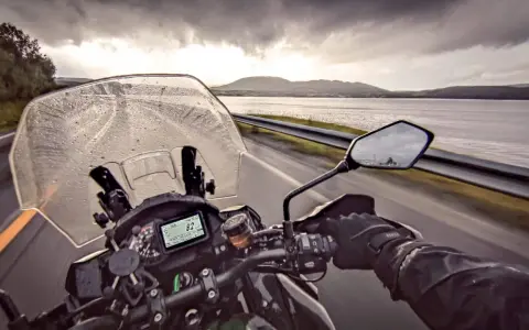 Jazda motocyklem w deszczu w kierunku Nordkapp. Pochmurne niebo i mokra droga nie zniechęcają do podróży.